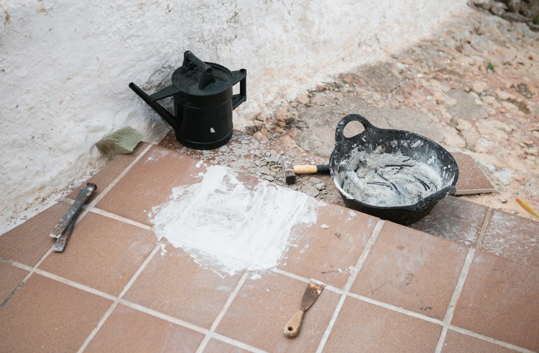 Floor tiling in progress with mortar, tools, and freshly laid tiles